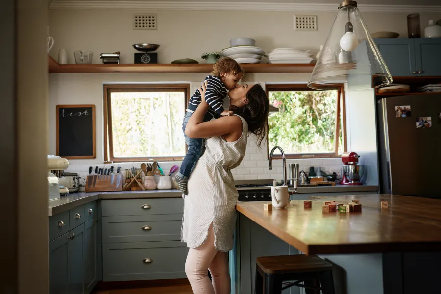 Madre cogiendo en brazos a su hija en la cocina mientras sonríen tras contratar la Tarifa Plana de Luz y Gas de Repsol